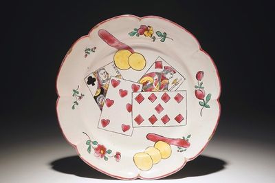 Een bord in Franse faïence met decor van speelkaarten, mog. Ferrat, Moustiers, of Nevers, 18e eeuw