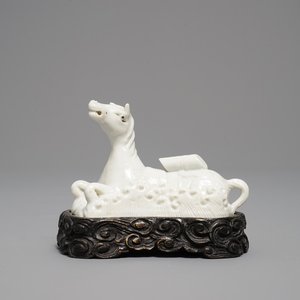 Een Chinees Dehua blanc de Chine model van een liggend paard op houten basis, Kangxi — foto 1