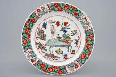 Een Chinees famille verte bord met een zotje op een tafel, Kangxi