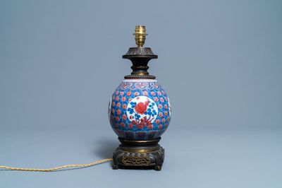 Een Chinese blauw-witte en koperrode vaas met vergulde bronzen lampmontuur, 19e eeuw