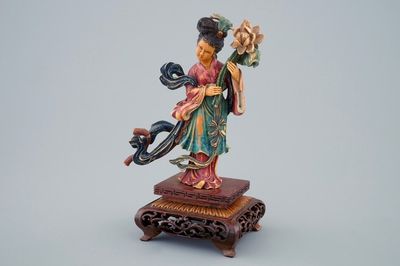 Een Chinese polychrome ivoren dame met bloem op houten sokkel, begin 20e eeuw