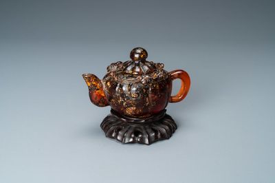 Een Chinese theepot in amber op houten 'lotus' sokkel, 19e eeuw