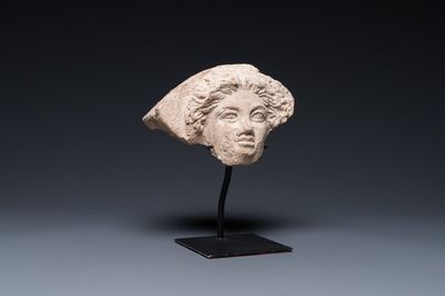 Een Griekse antefix in de vorm van een vrouwenhoofd in terracotta met wit slibglazuur, 5/4e eeuw v.C.