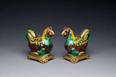 Een paar Chinese sancai geglazuurde kipvormige kannen gemonteerd als kandelaars met verguld brons, Kangxi
