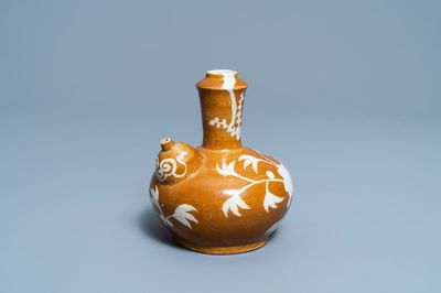 Een zeldzame Chinese Swatow kendi met floraal decor op bruine fondkleur, Ming