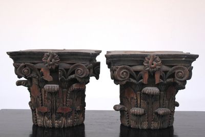Paire de grands chapitaux en bois d'après l'Antiquité, atelier De Wispelaere, Bruges, 1e moitié 20e