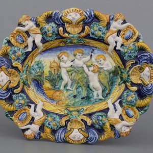 Polychrome ovalen schotel in reliëfvorm met putti die een geit onthoornen, 18e-19e eeuw — foto 1