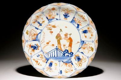 Un grand plat en porcelaine de Chine de style Imari à décor de femmes dans un jardin, Kangxi/Yongzheng