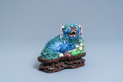 Un groupe en porcelaine de Chine figurant un lion bouddhiste et son lionceau sur socle en bois, 19ème