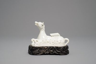 Un modèle d'un cheval en porcelaine blanc de Chine de Dehua sur socle sculpté, Kangxi