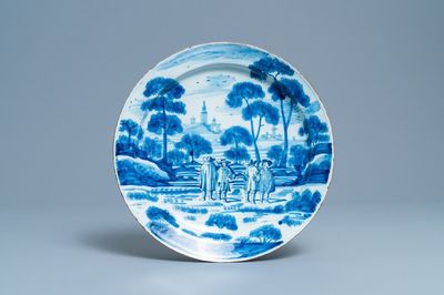Un plat en faïence de Delft en bleu et blanc à décor de figures dans un paysage, 18ème