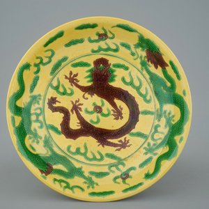 Un plat en porcelaine de Chine à décor de dragons en vert et aubergine sur fond jaune, marque de Kangxi, 19ème — photo 1