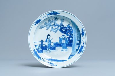 Un plat en porcelaine de Chine en bleu et blanc à décor de figures dans un jardin, Kangxi