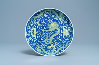 Un plat en porcelaine de Chine en bleu et jaune à décor d'un dragon, marque et époque de Qianlong