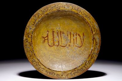 Un plat islamique en pierre sculptée à décor petit feu de calligraphie et un cadre magique sur le dos, 16/17ème