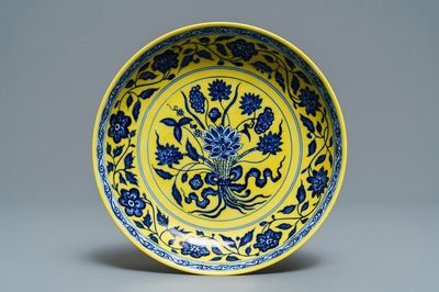 Une assiette en porcelaine de Chine à décor d'un bouquet en bleu et blanc sur fond jaune, marque de Qianlong, 19/20ème