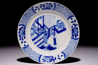 Une assiette en porcelaine de Chine bleu et blanc à décor de personnages dans un jardin, marque et période de Kangxi