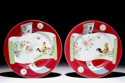 Une paire d'assiettes en porcelaine de Chine famille rose à décor de coqs sur fond rouge rubis, Yongzheng
