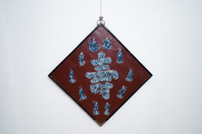 Une plaque laquée rouge incrustée de porcelaine de Chine en bleu et blanc, 19/20ème