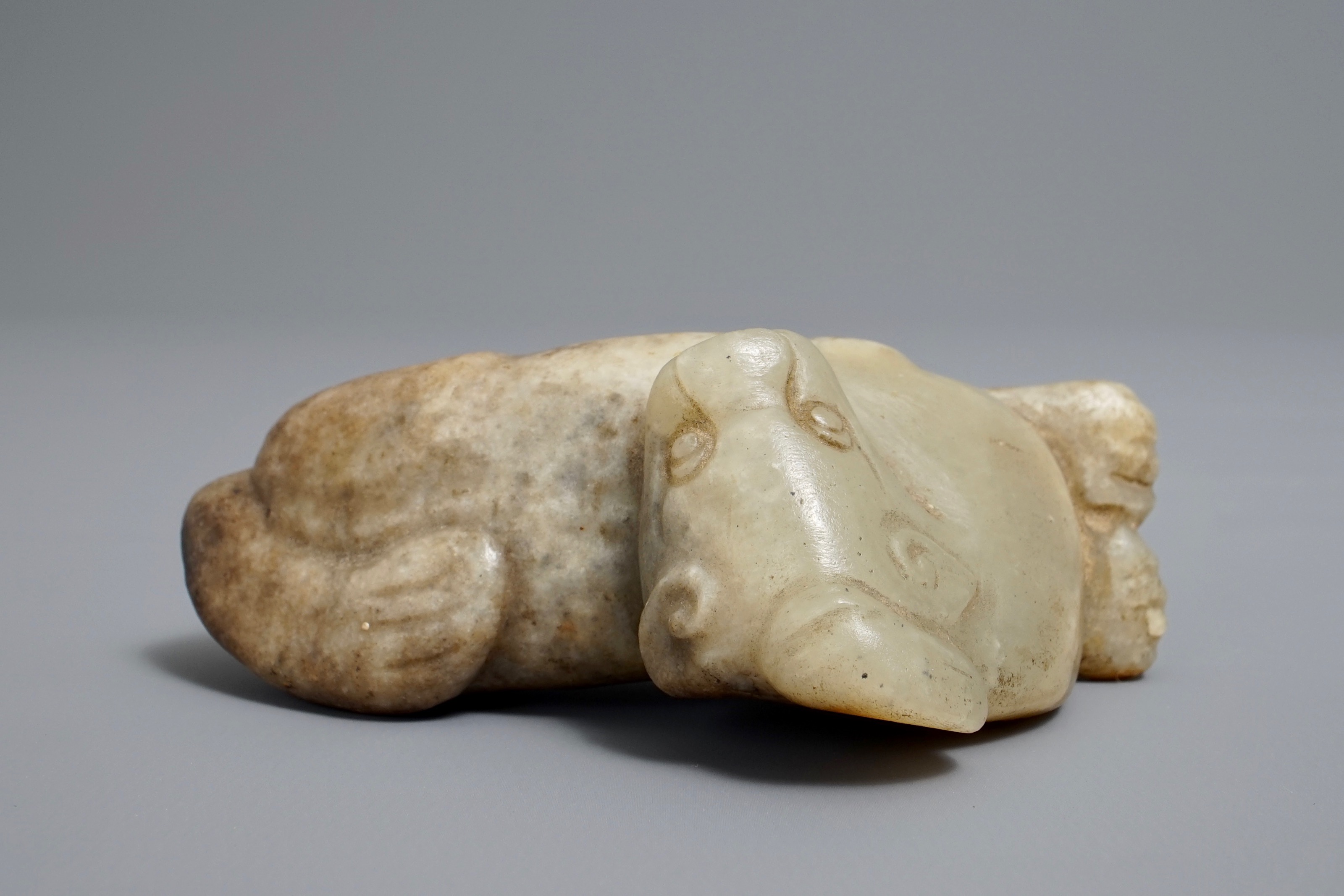 A Chinese pale greenish-grey and brown jade model of a mythical beast ...