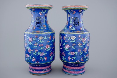 A pair of Chinese blue ground famille rose vases with flowers, 19th C.