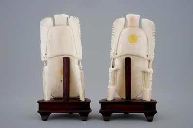 A pair of Chinese carved ivory faces on wooden stands, 19th C.