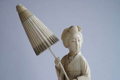 A Japanese carved ivory okimono of a lady holding a parasol, 19th C.