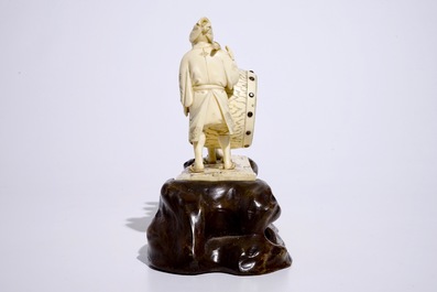 A large Japanese ivory okimono of boys playing a drum on a carved wooden base, Meiji, late 19th C., signed