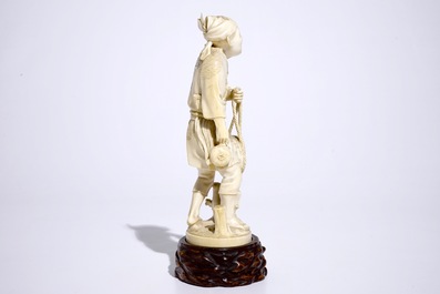 A Japanese ivory okimono of a fisherman on wooden base, Meiji, 19th C., signed