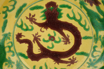 Un plat en porcelaine de Chine &agrave; d&eacute;cor de dragons en vert et aubergine sur fond jaune, marque de Kangxi, 19&egrave;me