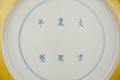 Un plat en porcelaine de Chine &agrave; d&eacute;cor de dragons en vert et aubergine sur fond jaune, marque de Kangxi, 19&egrave;me