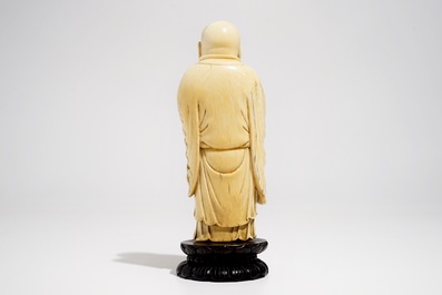 A Chinese carved ivory figure of Buddha holding a fan, on lotus-shaped base, 19th C.