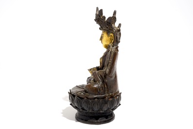 A partly gilt Chinese bronze figure of Buddha seated on a lotus throne, late Ming