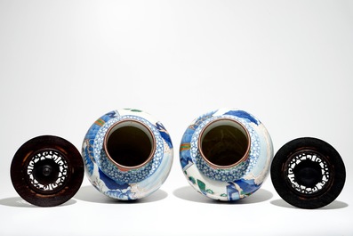 A pair of Chinese wucai baluster vases with carved lids and bases, 19th C.