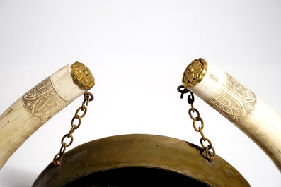 Un gong chinois en laiton orn&eacute; de deux d&eacute;fenses en ivoire sculpt&eacute;, 19/20&egrave;me