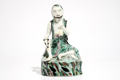 A Chinese verte biscuit model of a luohan with a scroll, Kangxi