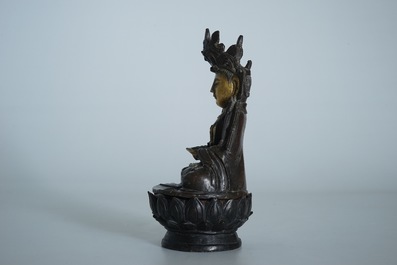 A partly gilt Chinese bronze figure of Buddha seated on a lotus throne, late Ming