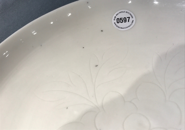 Un plat en porcelaine blanc de Chine &agrave; d&eacute;cor floral incis&eacute;, Kangxi