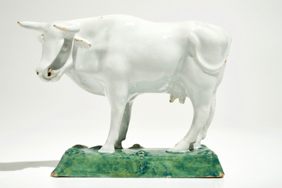 A white Dutch Delft model of a cow on a green base, 18th C.