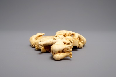 A Japanese carved ivory okimono with oni around a screen, signed, Meiji, 19th C.