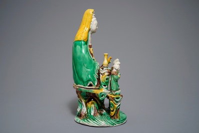 A Chinese verte biscuit group of Guanyin on a lotus throne, 18th C.