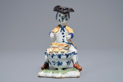 A polychrome Dutch Delft model of a man near a stove, 18th C.