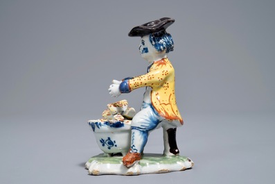 A polychrome Dutch Delft model of a man near a stove, 18th C.