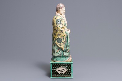 A large Chinese verte biscuit figure of an immortal on reticulated stand, Kangxi
