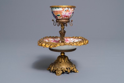 Une tasse et soucoupe en porcelaine de Chine famille rose &agrave; monture en m&eacute;tal dor&eacute;, Qianlong et 19&egrave;me