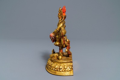 A Sino-Tibetan painted gilt bronze figure of Jambhala on a dragon, 19/20th C.