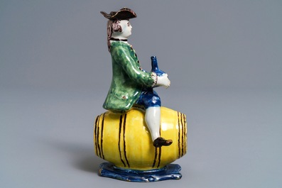 A polychrome Dutch Delft figure of a man on a barrel, 18th C.