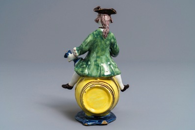 A polychrome Dutch Delft figure of a man on a barrel, 18th C.