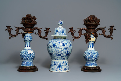 A Dutch Delft blue and white three-piece garniture with carved wooden candleholders, 18th C.