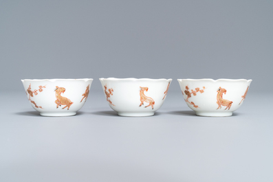 Three Chinese iron red eggshell cups and saucers with boys and goats, Yongzheng